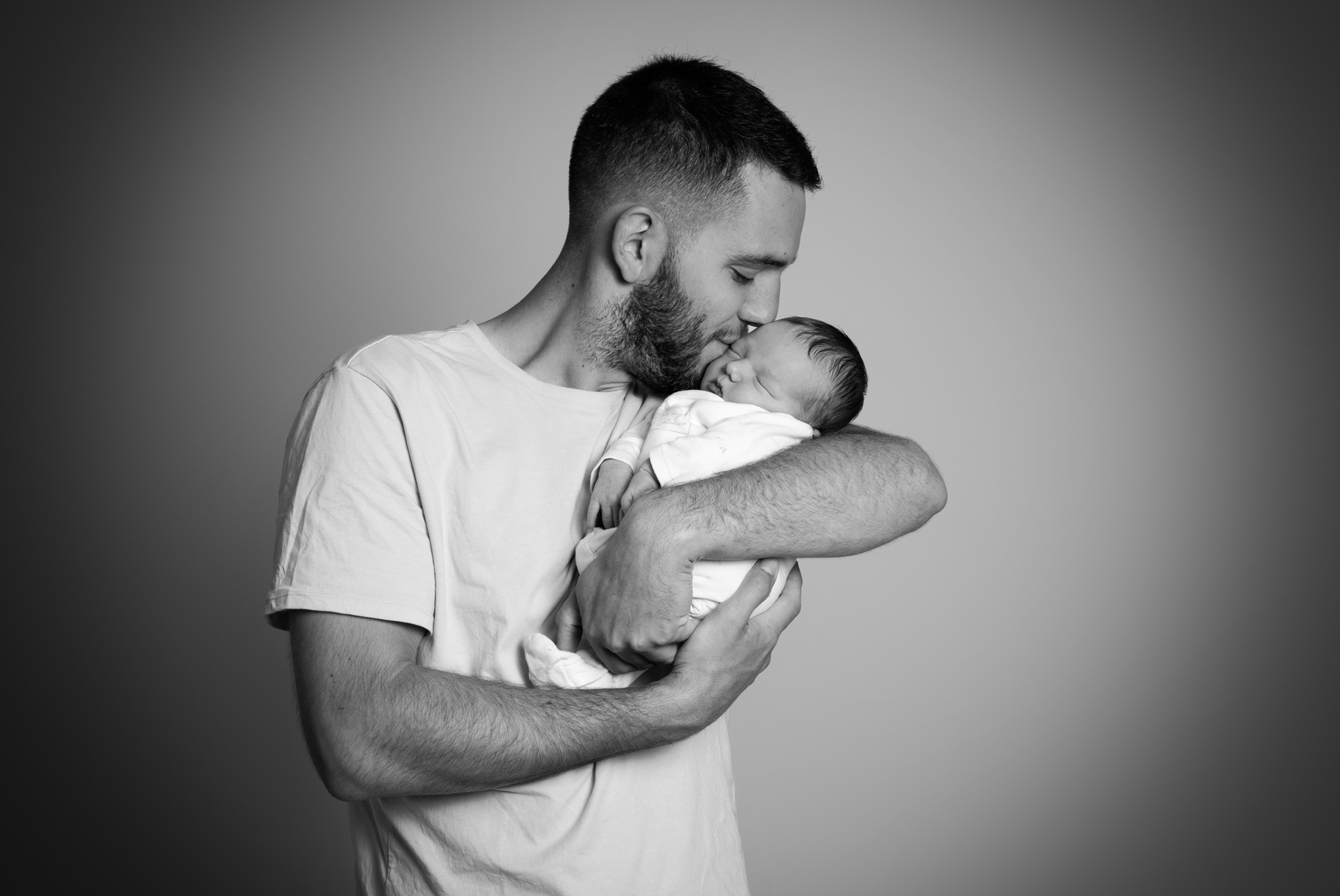 Papa embrassant tendrement son nouveau-né lors d’une séance photo naissance à Bressuire